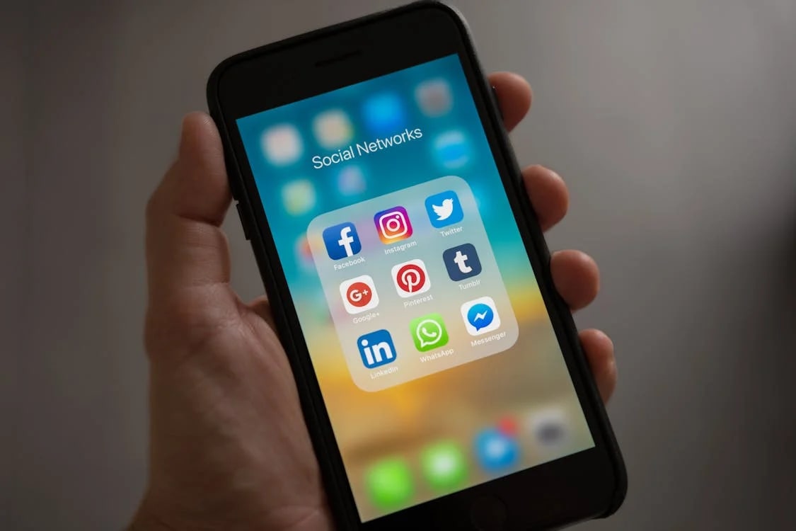 Person holding phone showing icons of social media channels