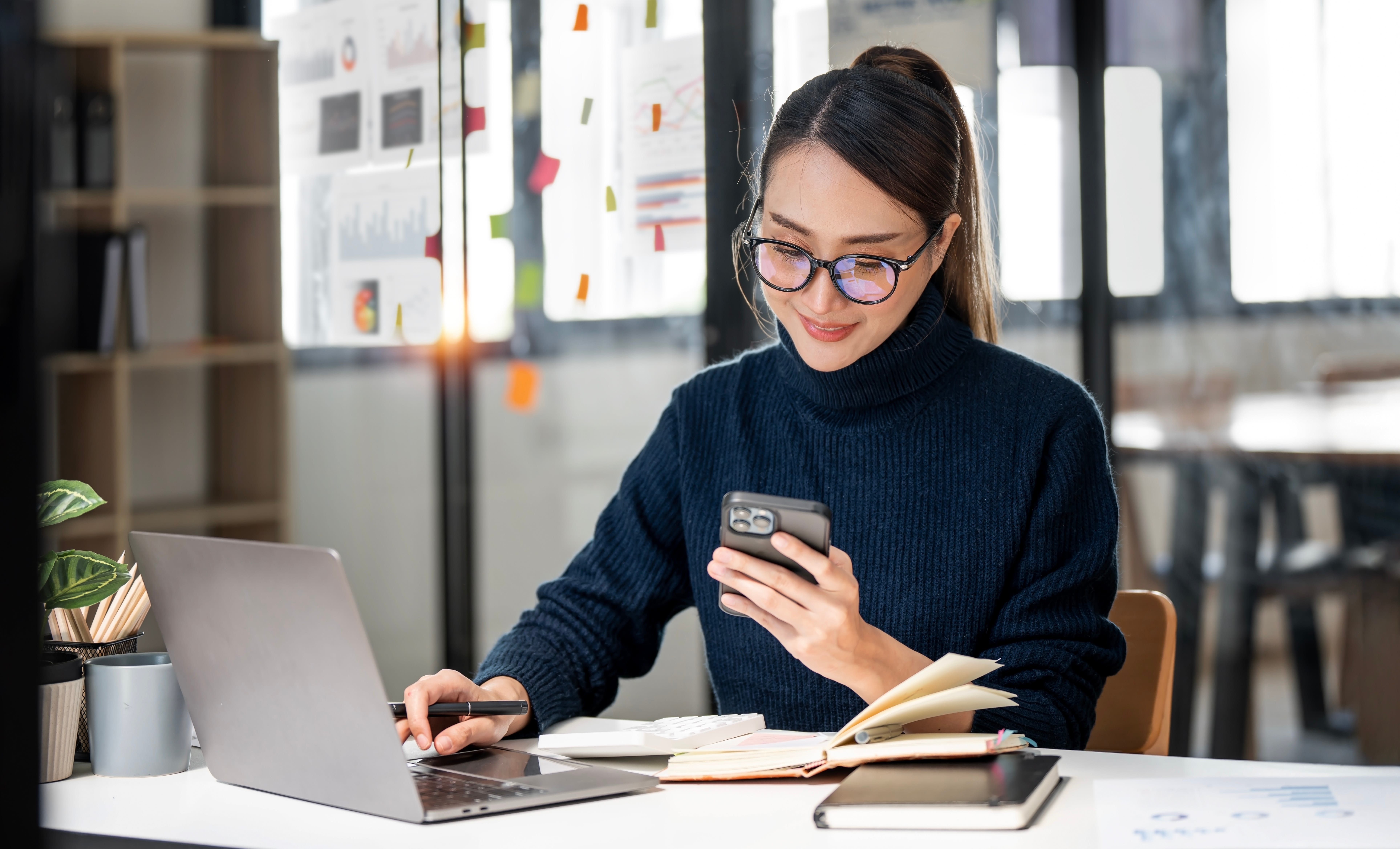 Woman in the office smiling while looking at her smartphone