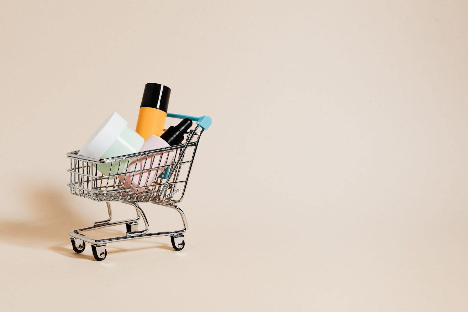 Abstract small shopping cart filled with products in a beige background