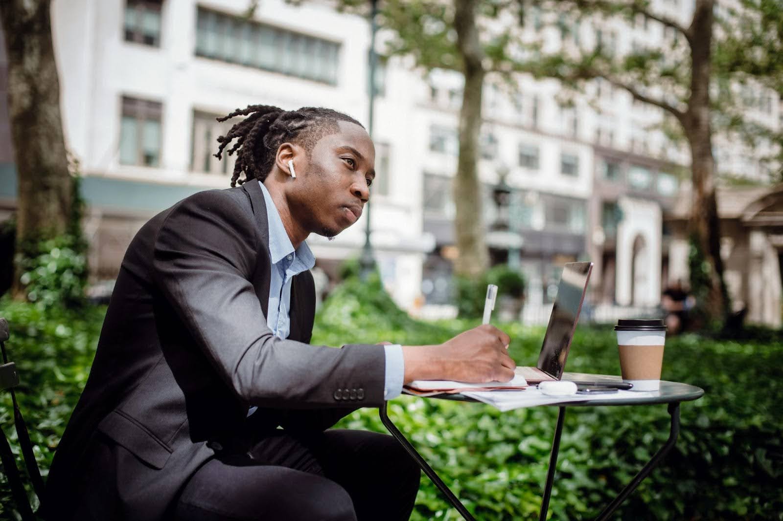 A man writing a book outside in deep thought