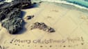 write your text on sand with natural shells and beach stones