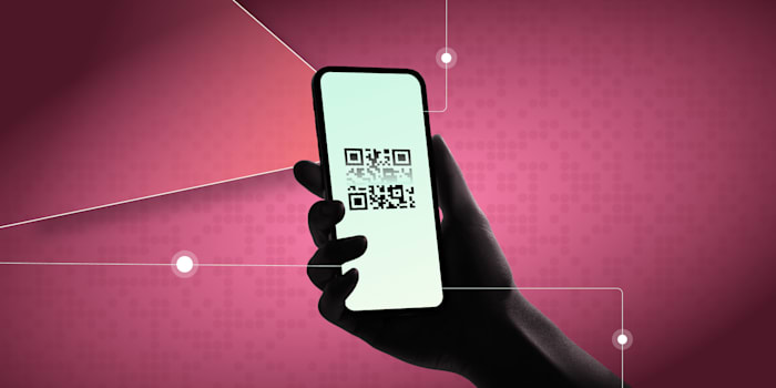 Silhouette of a hand holding a smartphone displaying a QR code on a pink digital background