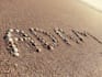 write your text on sand with natural shells and beach stones