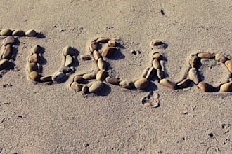 write your text on sand with natural shells and beach stones